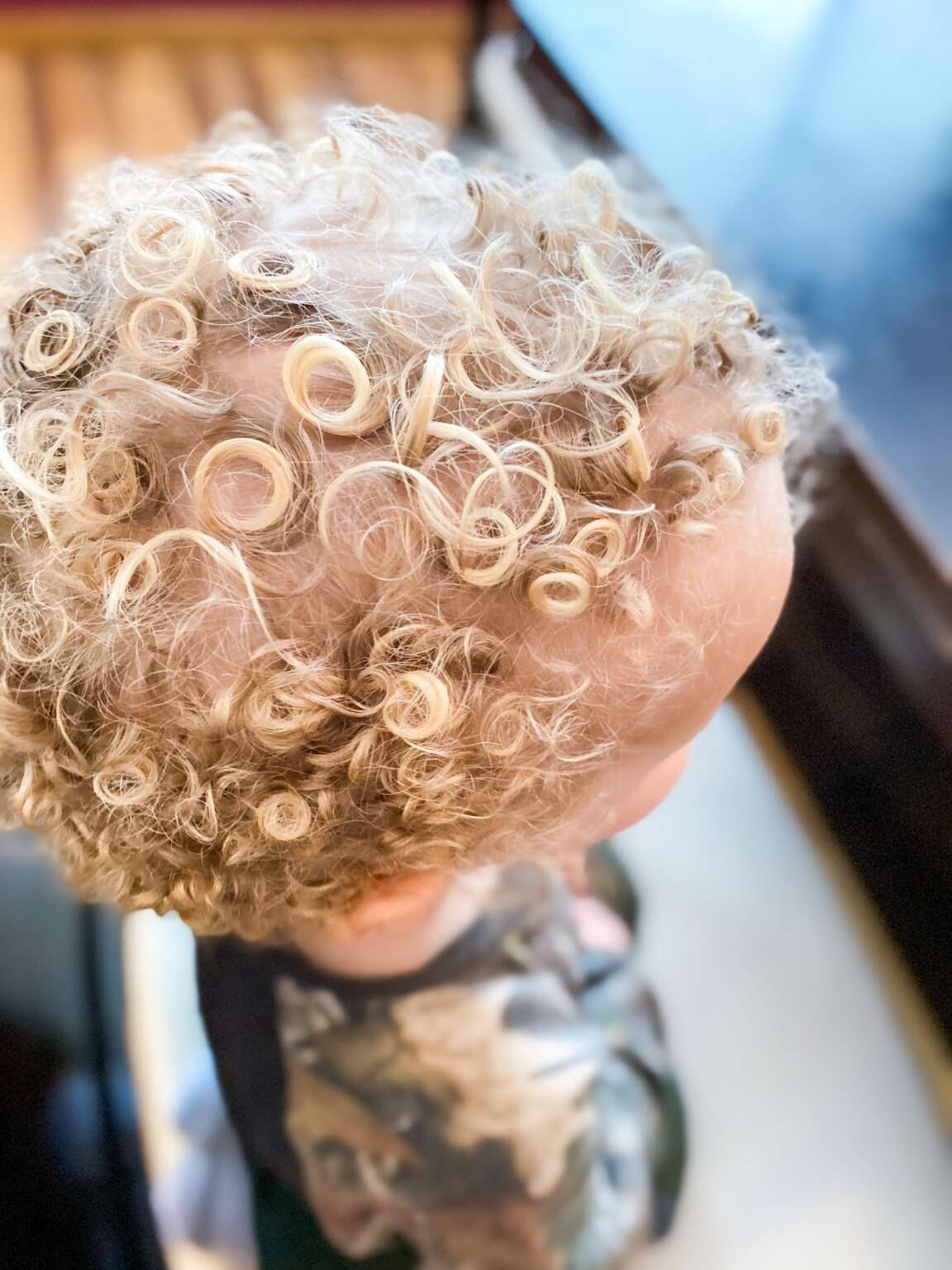 Stylist cutting curly child&rsquo;s hair with attention to curl pattern